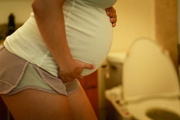A pregnant woman holding her bladder, rushing to the bathroom toilet